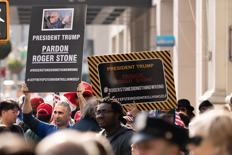 Pardon Roger Stone signs being held up during a Veterans Day Parade in Manhattan