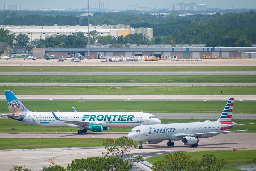 Frontier and American Airlines aircraft on runway preparing for departure from the Orlando International Airport MCO. Orlando, Florida. July 09, 2019. 