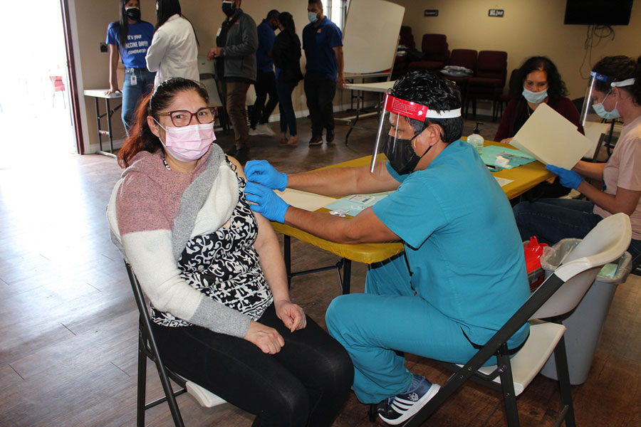 Dr. Marx Genovez, a family medicine doctor, prepares Guadalupe Neri’s arm for a covid-19 vaccine at El Sol Neighborhood Educational Center’s pop-up vaccination clinic on March 19, 2021 in Adelanto, California. Neri knows several friends who have tested positive for covid. Without this event, she says, she wouldn’t know where to get a shot. 