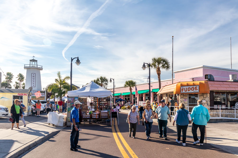Tourist and locals shopping at the historic beach downtown street festival with restaurant food and arts craft merchandise vendors with some retail business.